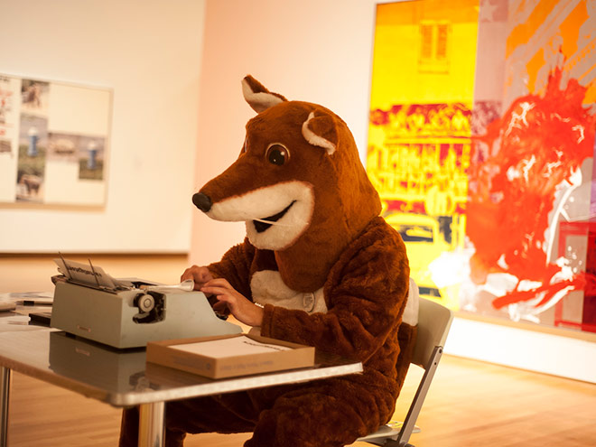 Photo of a person dressed in a fox costume typing on a typewriter